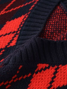 Détail du col en V côtelé et du motif à losanges rouge et bleu sur le gilet en maille