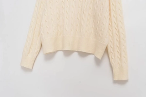 Detailed cable-knit texture on cream crew neck sweater with ribbed cuffs and hem