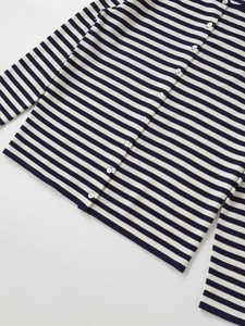 Gros plan du cardigan en maille à rayures bleues et blanches avec petits boutons blancs