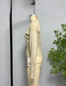 Detail einer beigen Strickjacke mit Knopfmanschetten und Rippsaum auf einer Schneiderpuppe
