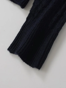 Close-up of navy blue alpaca wool knit sweater showing textured cable stitch and ribbed cuffs