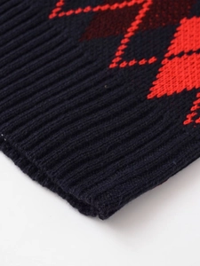 Gros plan d'un gilet en maille bleu marine avec motif losange rouge et bord côtelé