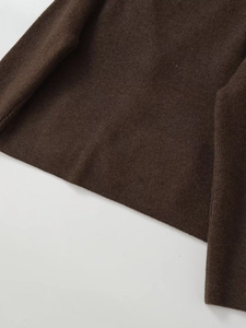 Detail of dark brown knit sweater showing fine texture and hemline craftsmanship