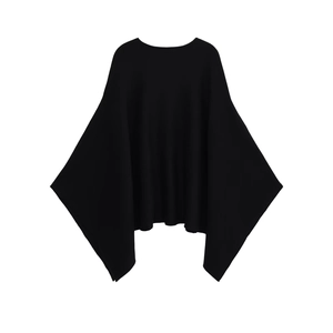 Detail of loose black knit poncho featuring batwing sleeves and a minimalist round neck