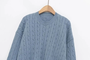 Close-up of thick cable knit texture and ribbed crew neck on gray-blue sweater