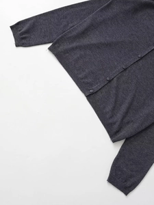 Détail d'un cardigan gris foncé montrant l'ourlet côtelé et les boutons assortis