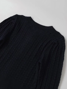 Detail of round neckline and textured hollow knit pattern on black long sleeve sweater
