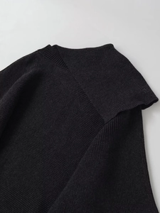 Close-up of the asymmetric neckline and ribbed knit texture of a black sweater