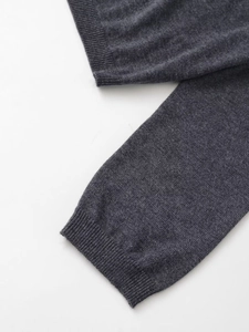 Gros plan sur les poignets côtelés et l'ourlet d'un cardigan gris à col en V en tricot