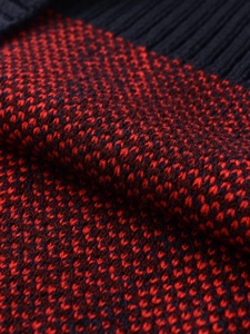 Détail macro du gilet en tricot à losanges rouge et noir avec bordure côtelée