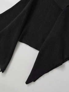 Detail of black ribbed knit cardigan showing the soft fabric texture and asymmetric hem