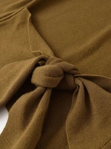 Macro detail of the elegant bow-knot design on a ginger yellow long-sleeve knit sweater
