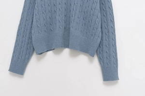 Detail of light blue cable knit sweater showing ribbed cuffs and soft texture