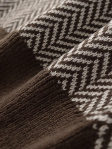 Macro shot of herringbone knit texture in dark brown and beige wool blend fabric