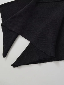 Close-up of black knitted shawl with fine ribbed texture and layered fabric details