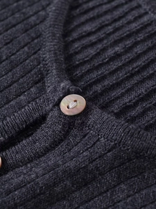 Détail de maille côtelée sur pull gris foncé avec bouton aux reflets nacrés chic