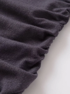 Detailed close-up of dark grey knitted fabric showing soft texture and ruched design details