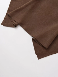 Close-up of dark brown knitted poncho fabric texture with fine edge stitching