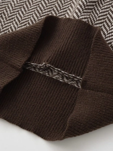 Detailed view of brown herringbone knit fabric with thick ribbed hem texture
