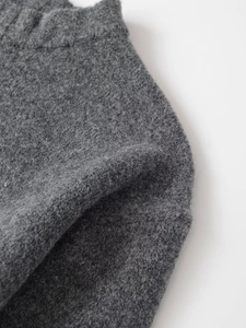 Detail of dark charcoal ribbed knit fabric showing thick wool texture and elastic waistband