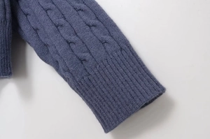 Close-up of cable knit texture and ribbed cuff on a navy blue round neck sweater