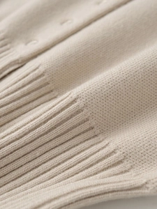 Detailansicht der Rippbündchen und der feinen beigen Stricktextur des Damenpullovers