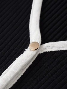 Détail de gilet en maille avec bordure blanche contrastée et bouton doré en métal