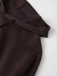 Detail of soft chocolate brown knit fabric with exposed seams and drawstring accents
