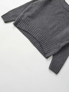Detail of dark grey ribbed knit sweater with focus on hem and cuff texture