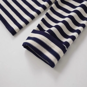 Gros plan de la manche du cardigan en tricot à rayures bleues et blanches avec côtes