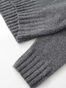 Detailed macro view of dark grey knit sweater showing ribbed cuffs and thick texture