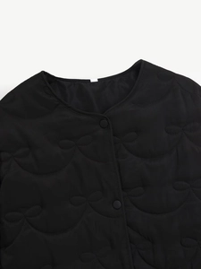 Detail view of black quilted jacket featuring round neck and bow-shaped stitching patterns