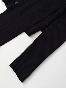 Detailed close-up of black ribbed knit fabric and secure round button on the cardigan