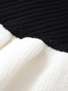 Détail macro du tricot côtelé montrant des coutures contrastées et des textures ajourées