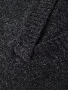 Detailed macro view of dark grey knit vest fabric showing soft wool texture and ribbed edge
