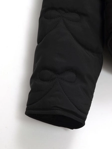 Detail of black matte jacket sleeve featuring unique bow-shaped quilting and fine stitching