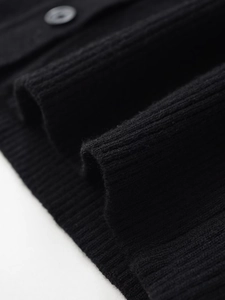 Close-up of black ribbed knit cardigan featuring vertical texture and matching round button