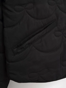 Detail of black onion quilted fabric texture with a diagonal welt pocket on the jacket