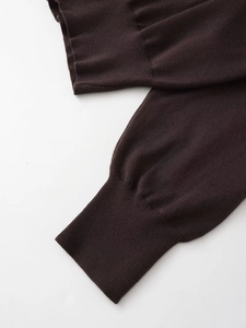 Detailed close-up of ribbed cuffs on a dark brown knit hoodie with soft texture