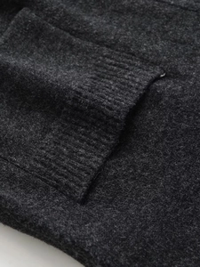 Detail of dark gray wool blend knit fabric showing soft texture and ribbed pocket edge