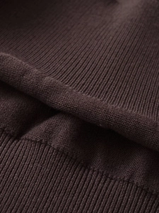 Close-up of deep brown knit fabric showing fine texture and elastic ribbed hem detail