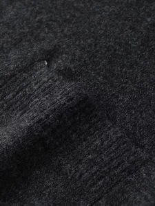 Macro detail of charcoal grey knit fabric showing soft ribbed texture and wool blend fibers
