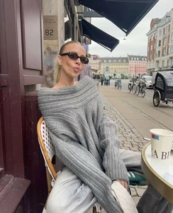 Detail of grey off-shoulder oversized knit sweater with chunky texture in street style