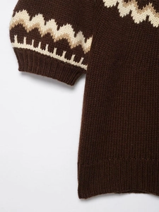 Detail of vintage Fair Isle pattern on a thick dark brown knit sweater with ribbed cuffs