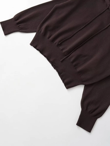 Close-up of dark brown knitted hoodie showing ribbed hem and soft fabric texture