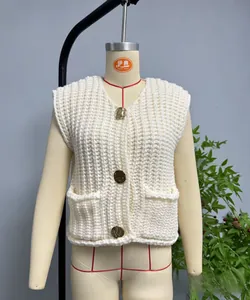 Detail of chunky knit vest featuring gold retro buttons and dual front patch pockets