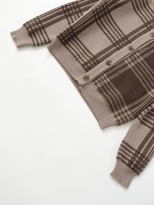 Detailed close-up of brown checkered knit cardigan with wooden buttons and ribbed cuffs