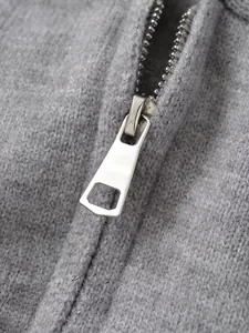 Close-up of a silver metal zipper on a grey knitted hooded cardigan for women