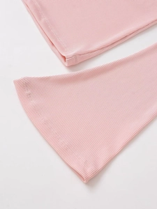 Gros plan sur la texture en maille côtelée rose et les détails des poignets évasés