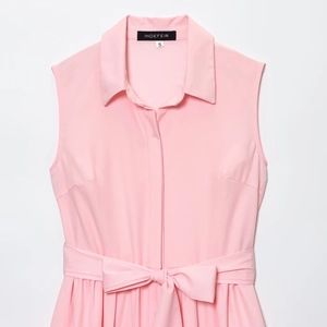 Detail of light pink sleeveless shirt dress featuring tie waist and branded neck label